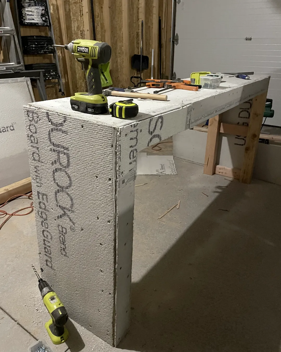The hallway table in the garage, mid-build, with a drill and a tape measure on top